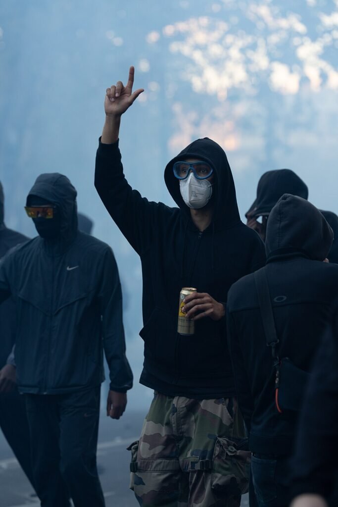 Archive photo from October 17, 2026: a masked demonstrator raises a hand amid tear gas during protests near Place de la République in Paris; not the October 24 demonstrations.