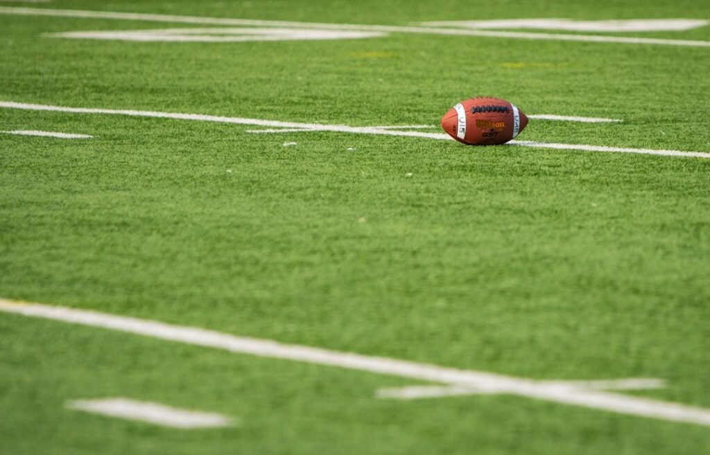 Illustrative photograph of an American football resting on a field; not a photograph of the October 25, 2026 Browns–Titans game.