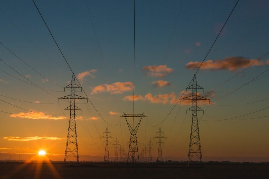 Electric transmission towers silhouetted at sunset, illustrative photograph of power-grid infrastructure, not an Alliant Energy project