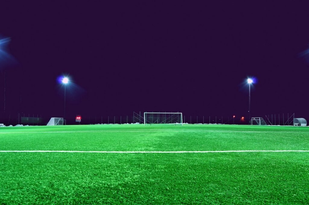 Illustrative football pitch illuminated by stadium floodlights at night; not a photograph of the Tottenham–Arsenal match