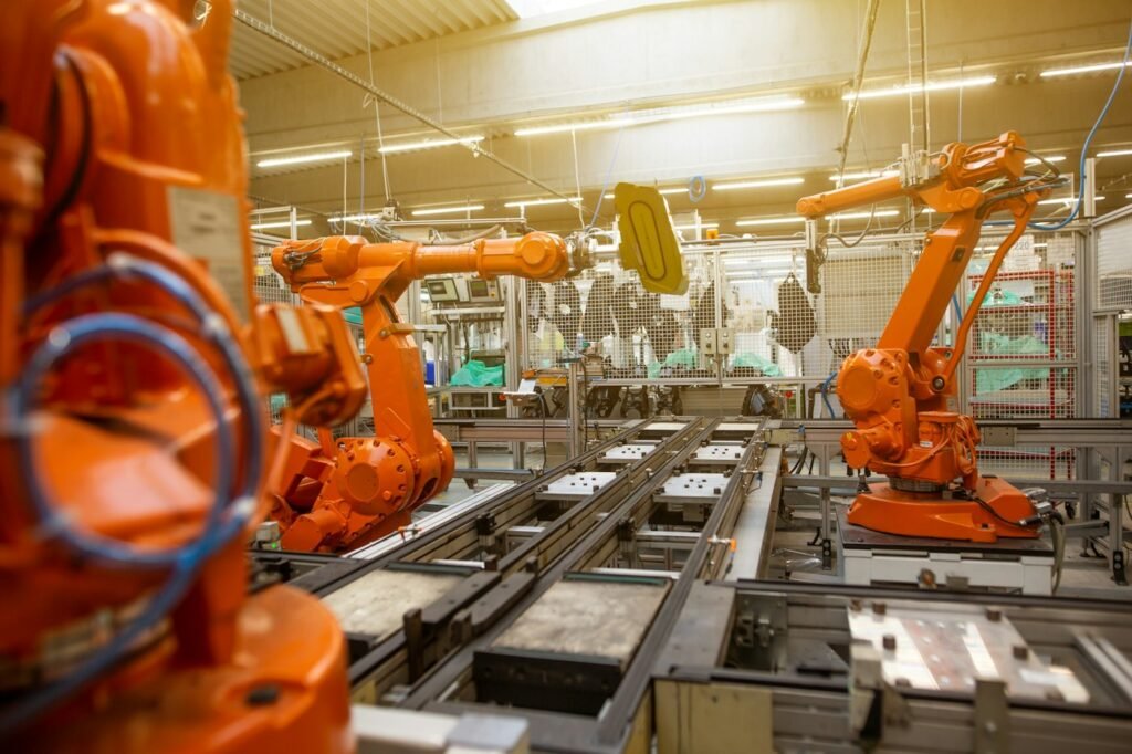 Orange industrial robotic arms working on an automotive assembly line; illustrative stock image, not a photo of the October 28, 2026 US trade announcement