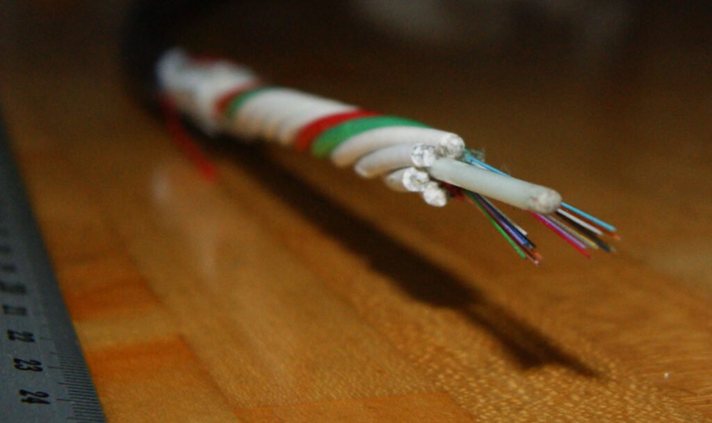 Close-up of a cut optical fibre cable showing coloured strands and protective layers, photographed in 2019; illustrative image, not Tata Communications infrastructure