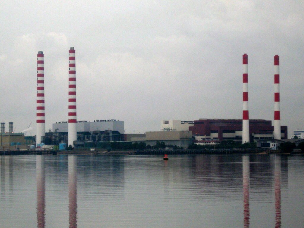 Archival view of Senoko Power Station in Singapore, with four red-and-white chimneys beside the water; photographed in February 2007.