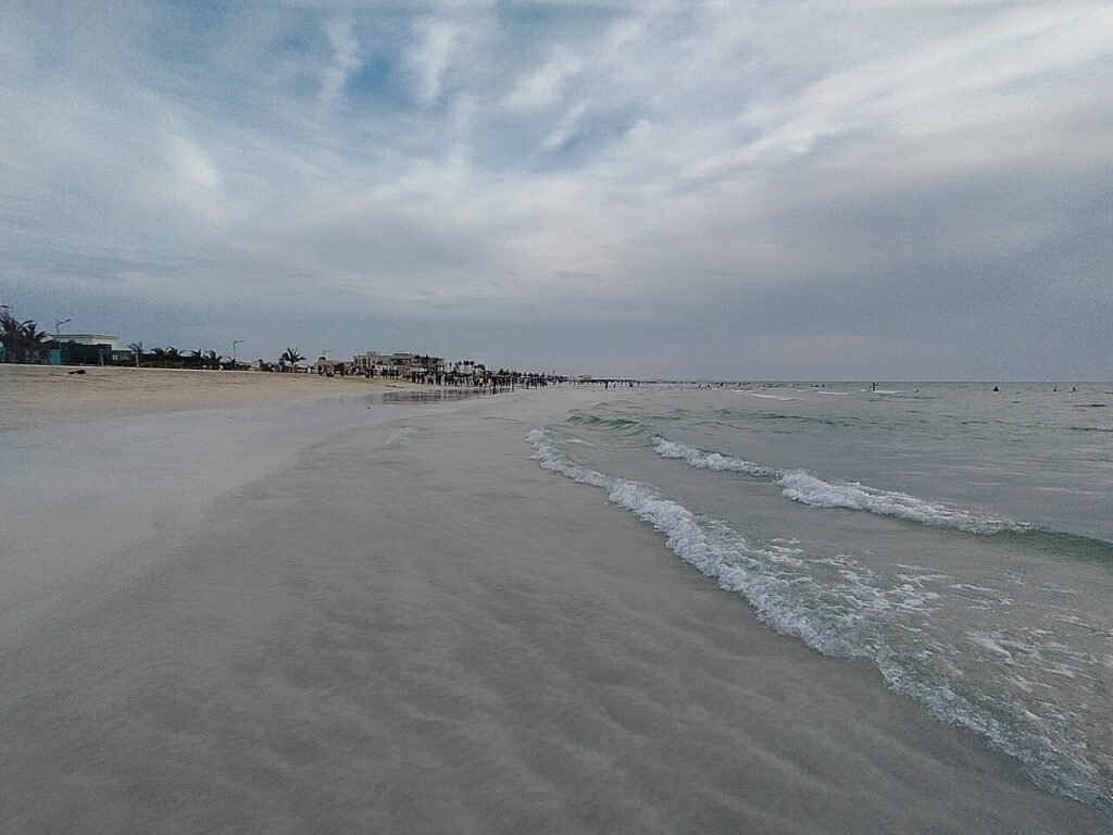 Archival April 2024 photograph of sandy Umm Al Quwain beach and gentle waves in the UAE, before the October 2026 oil spill; no current pollution shown.
